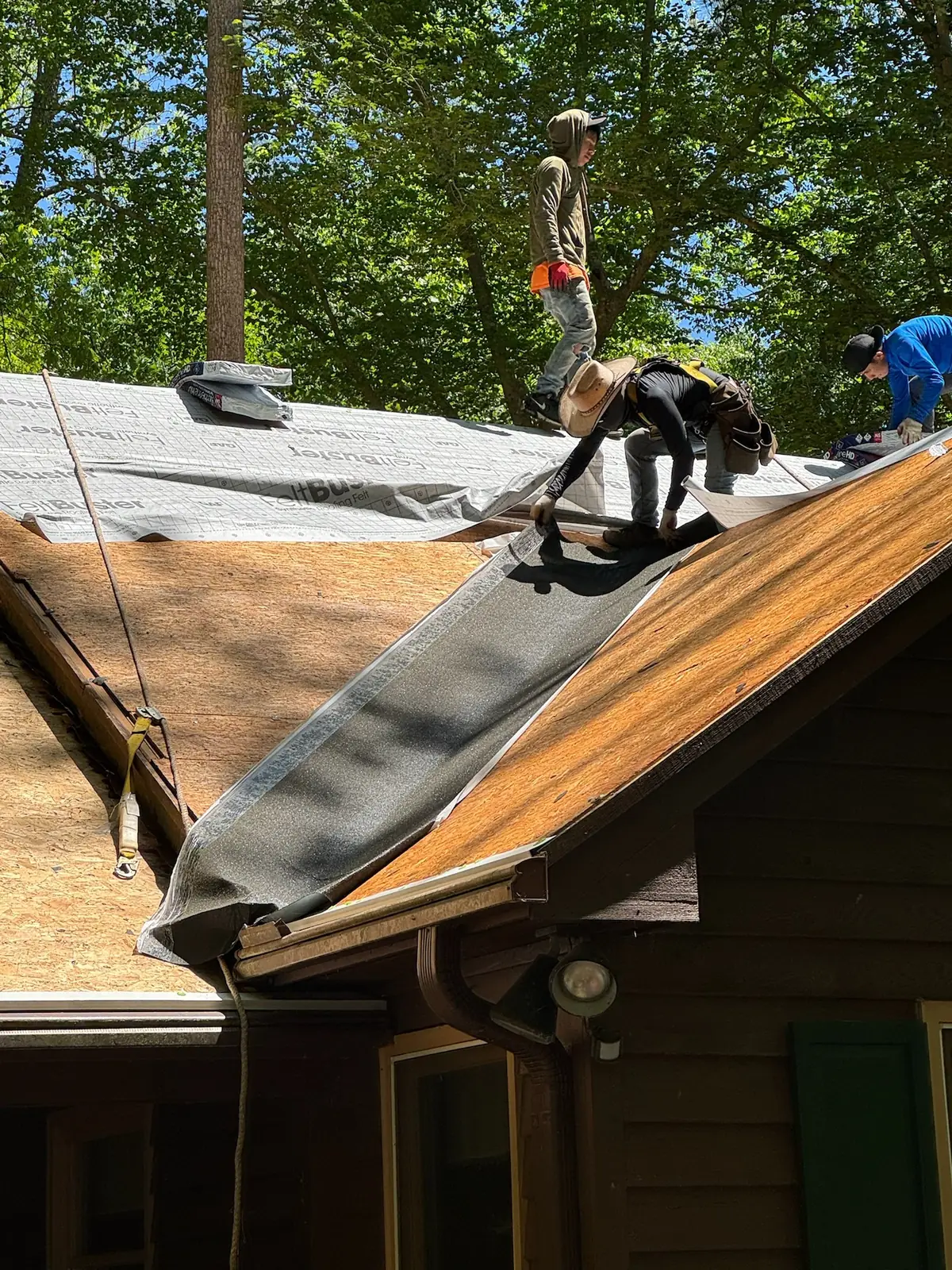 Crew tearing off an old roof on a wood-sided home