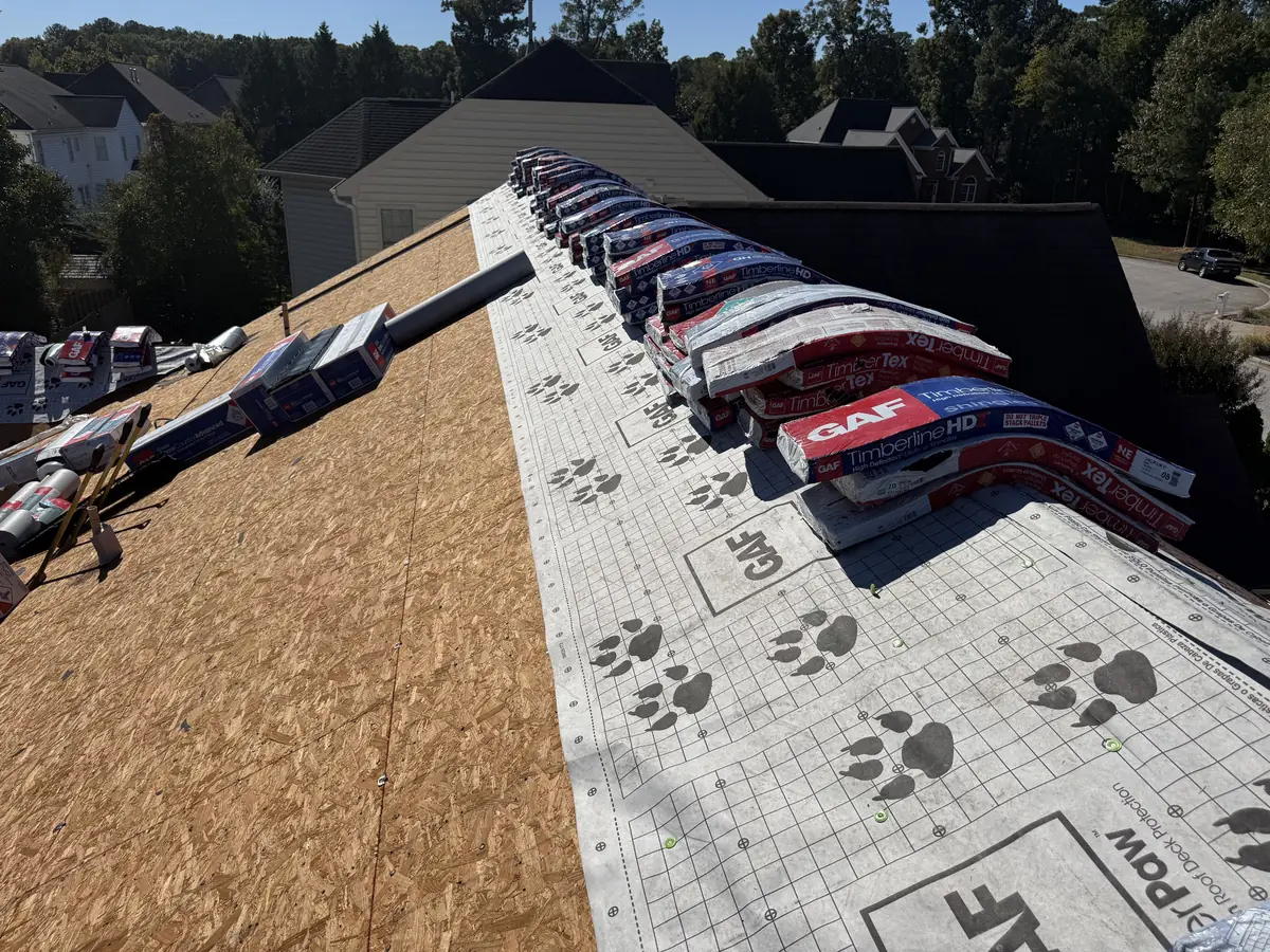 New OSB decking meeting GAF TigerPaw underlayment, with shingle bundles staged along the ridge