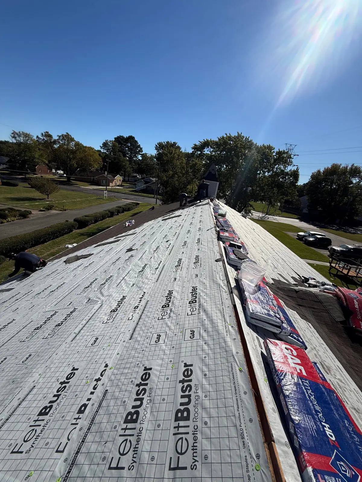 Crew working along a ridge covered in GAF FeltBuster synthetic underlayment