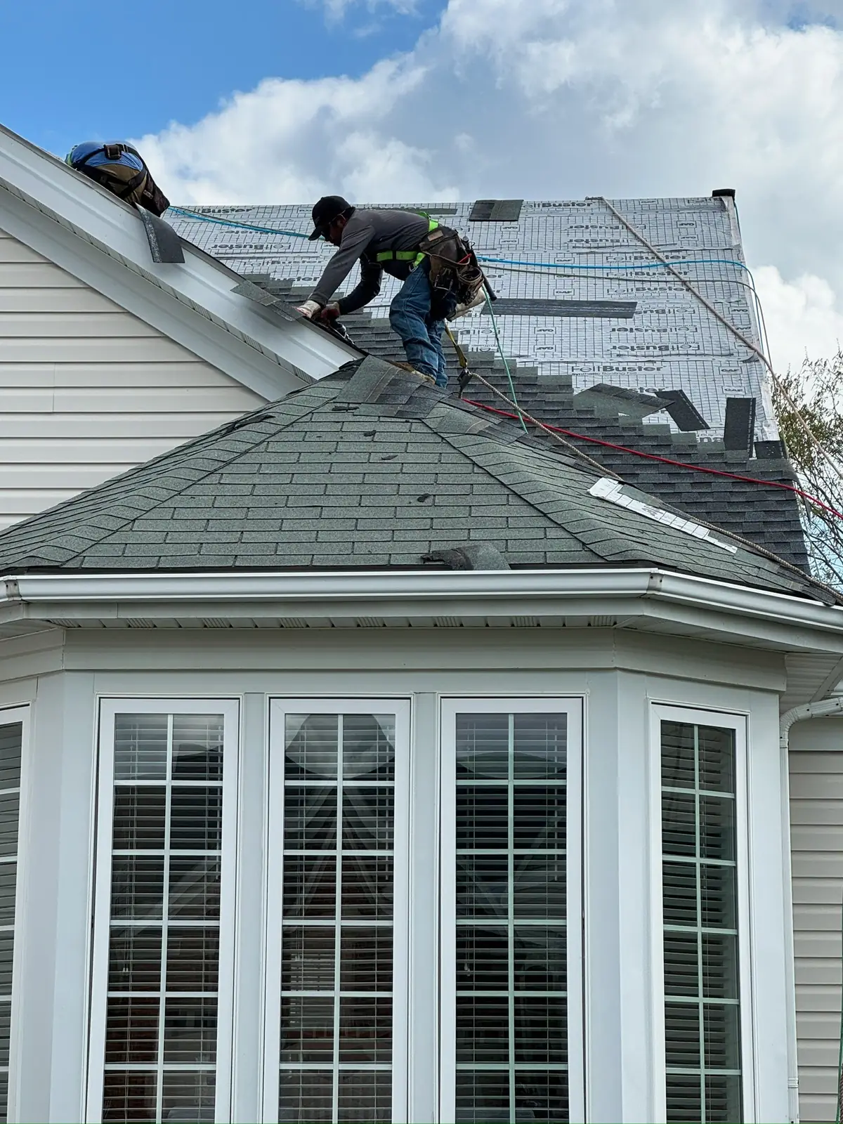 Roofer working on the roof above a bay window on a two-story home