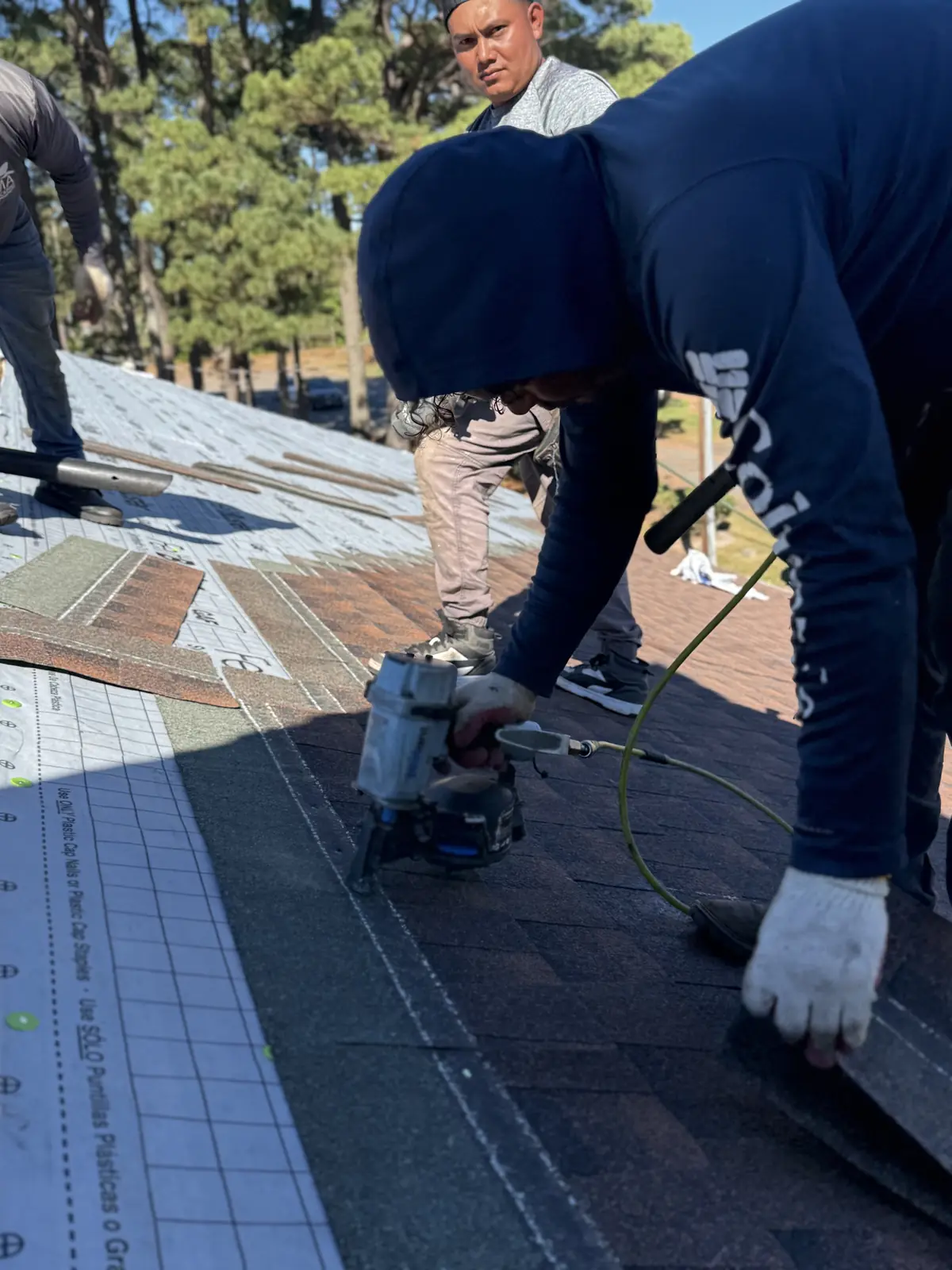 RoofTrue roofer nailing shingles with a nail gun
